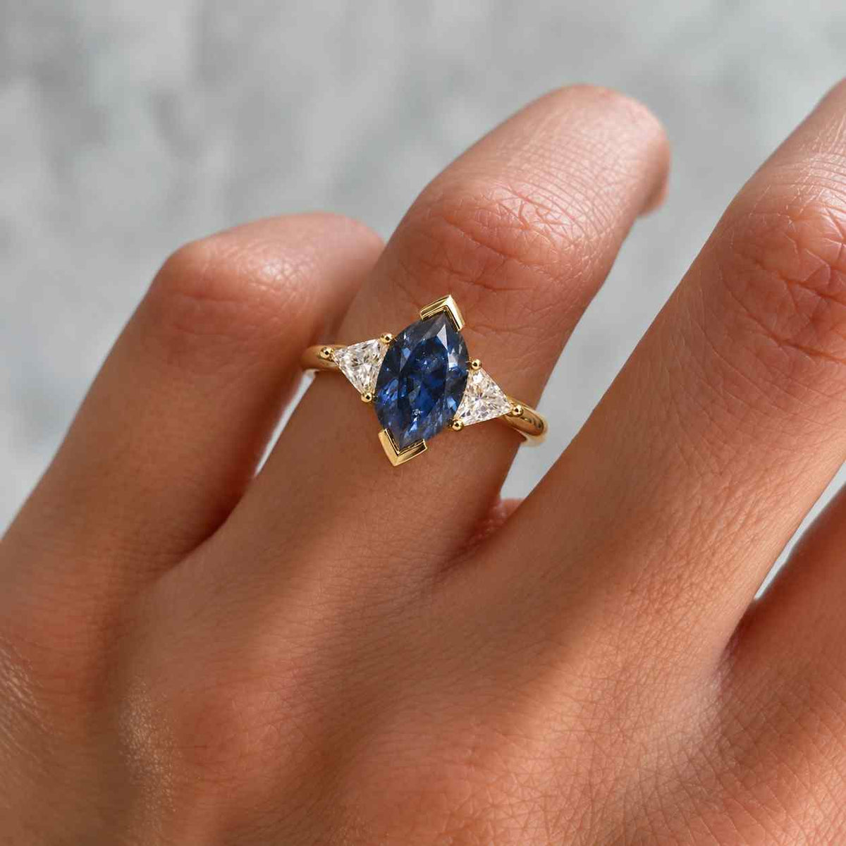 marquise blue sapphire engagement ring with lab diamond setting stones in 18k gold

